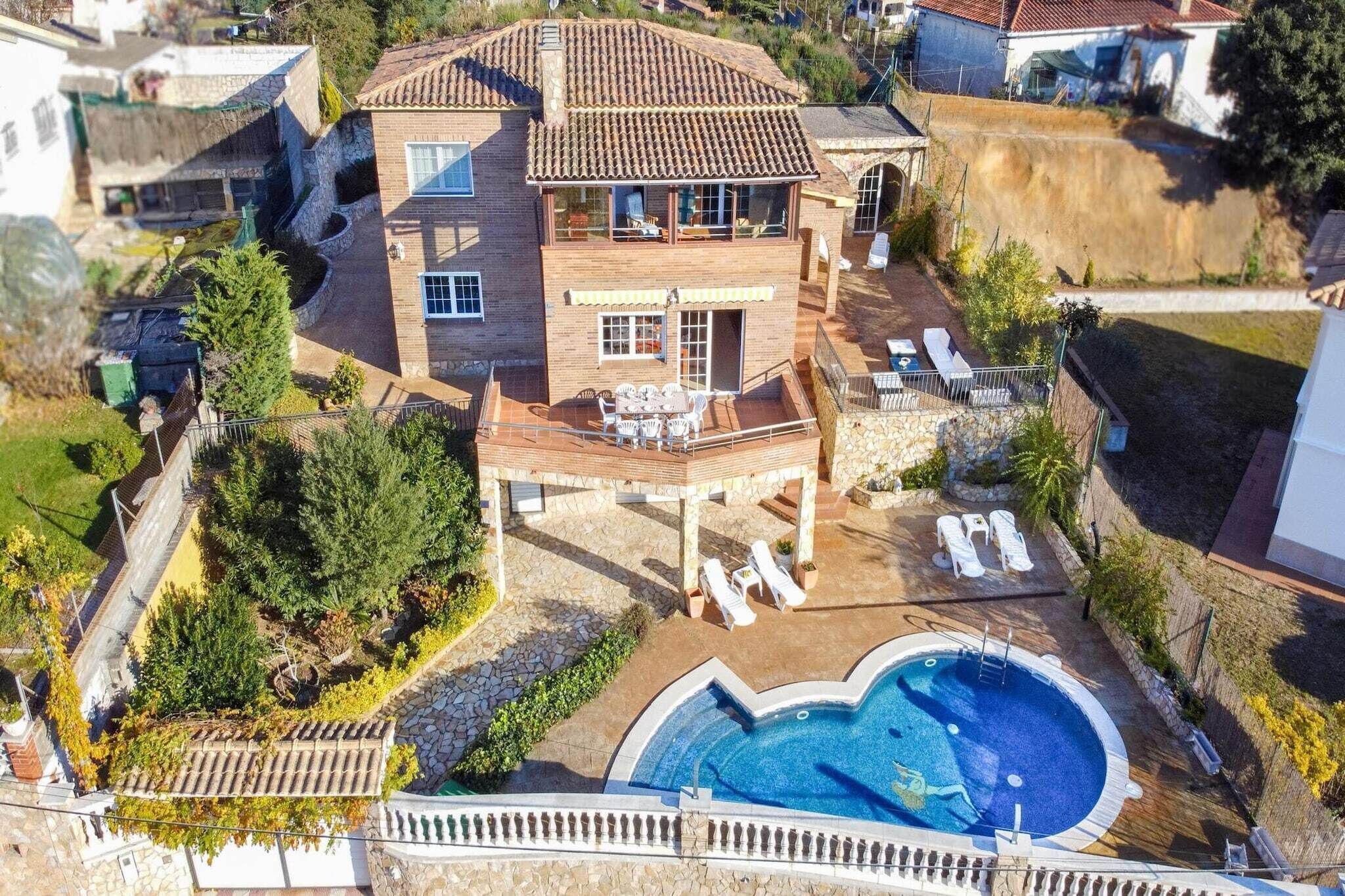 Una casa de dos pisos con piscina, un porche cubierto y un jardín.