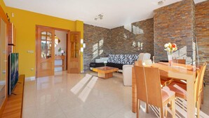 A modern living room with a sofa, coffee table, and dining area.