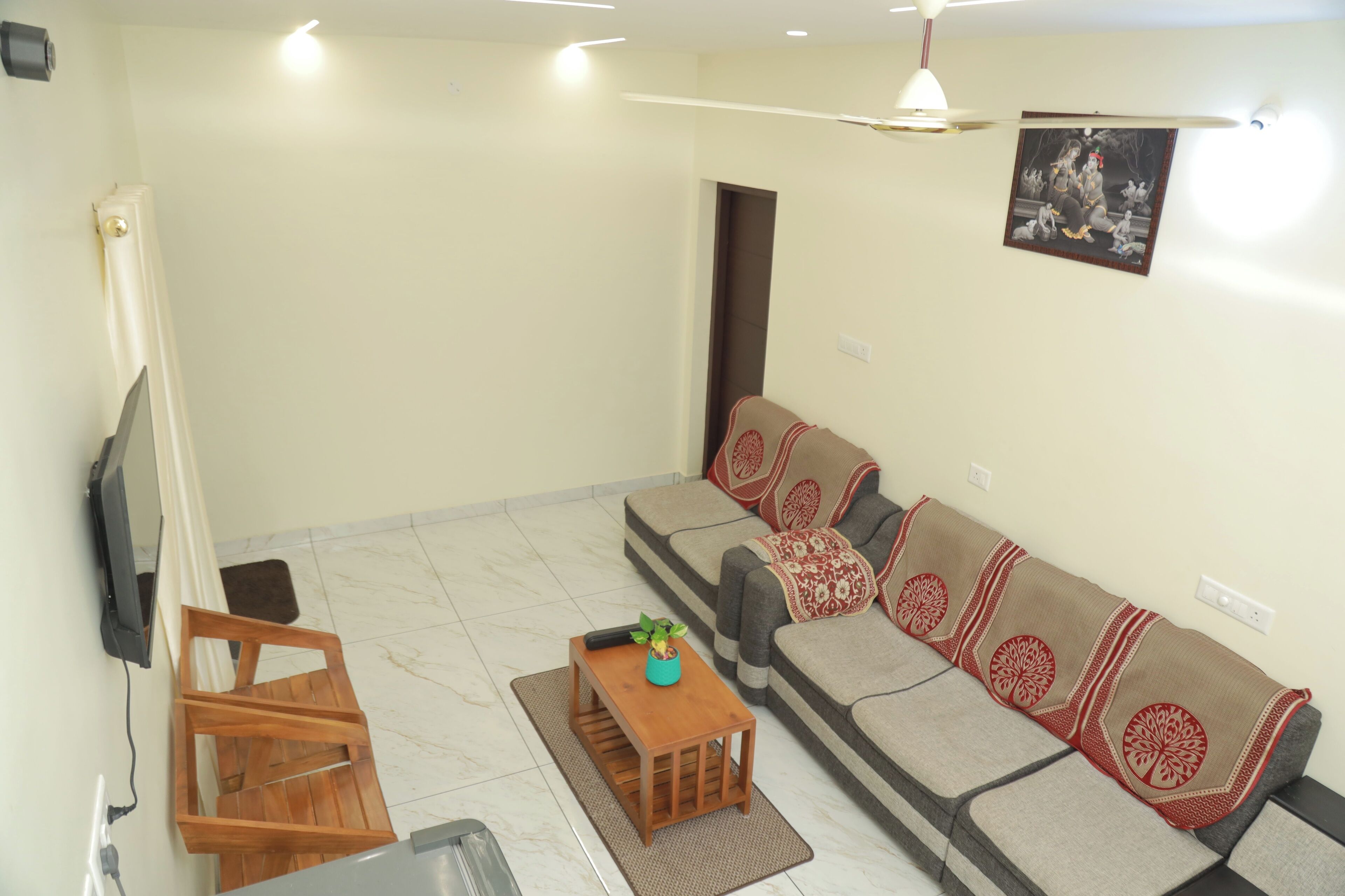 A living room with a sofa, a coffee table, a TV, and a door.
