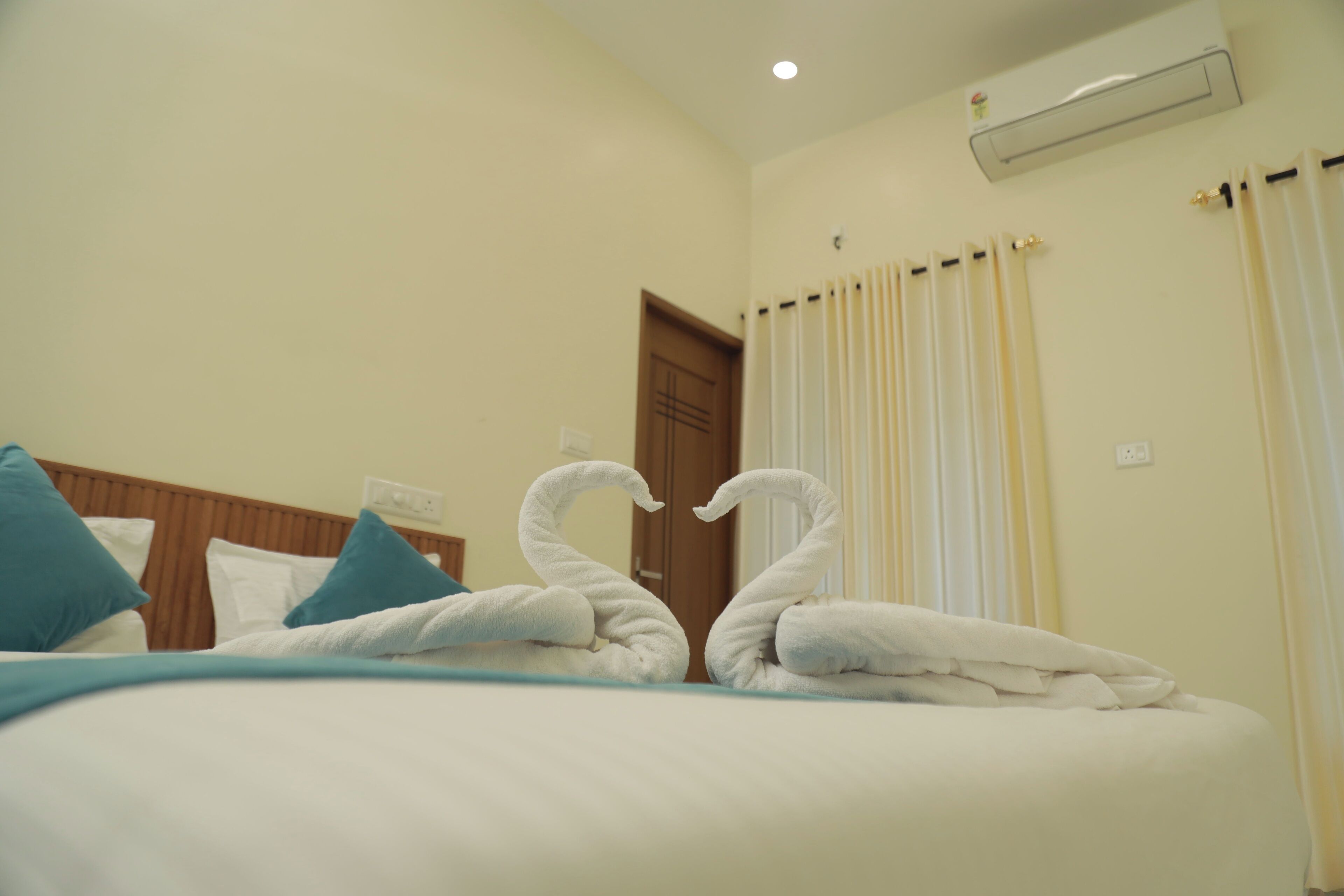 Ein Hotelzimmer mit einem ordentlich bezogenen Bett, einem hölzernen Kopfteil und einer Wand-Klimaanlage.