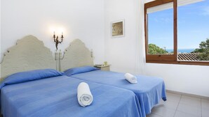 A room with two beds, a window with a view, and a wall-mounted light fixture. - Apartment in Llafranc near Beach & Pool (Llafranc)