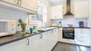 A modern kitchen with white cabinets, a built-in oven, and a window providing natural light. - Apartment in Llafranc near Beach & Pool (Llafranc)