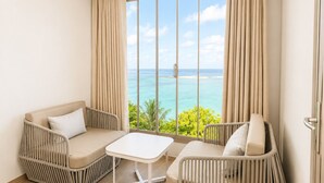 Una habitación con vista al océano, que incluye un sofá, una mesita y una silla.