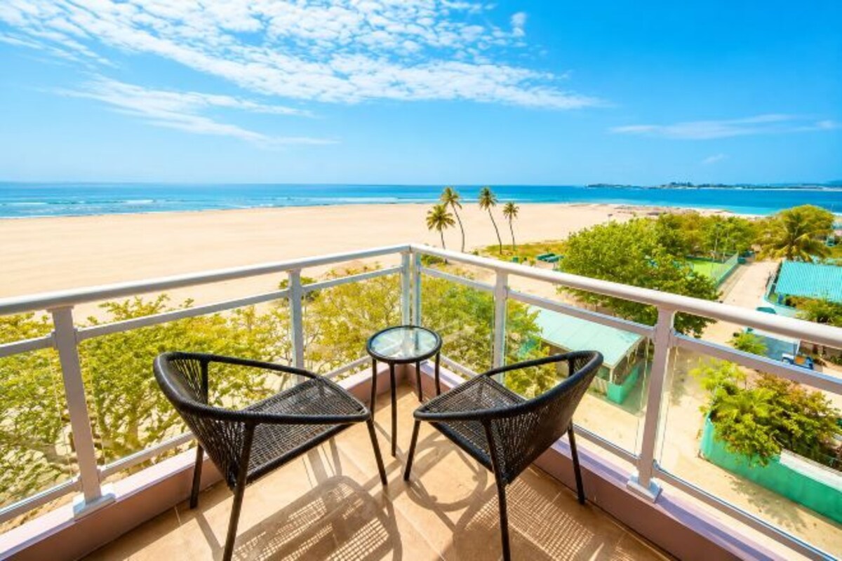 Un balcon avec deux chaises et une table donnant sur une plage.