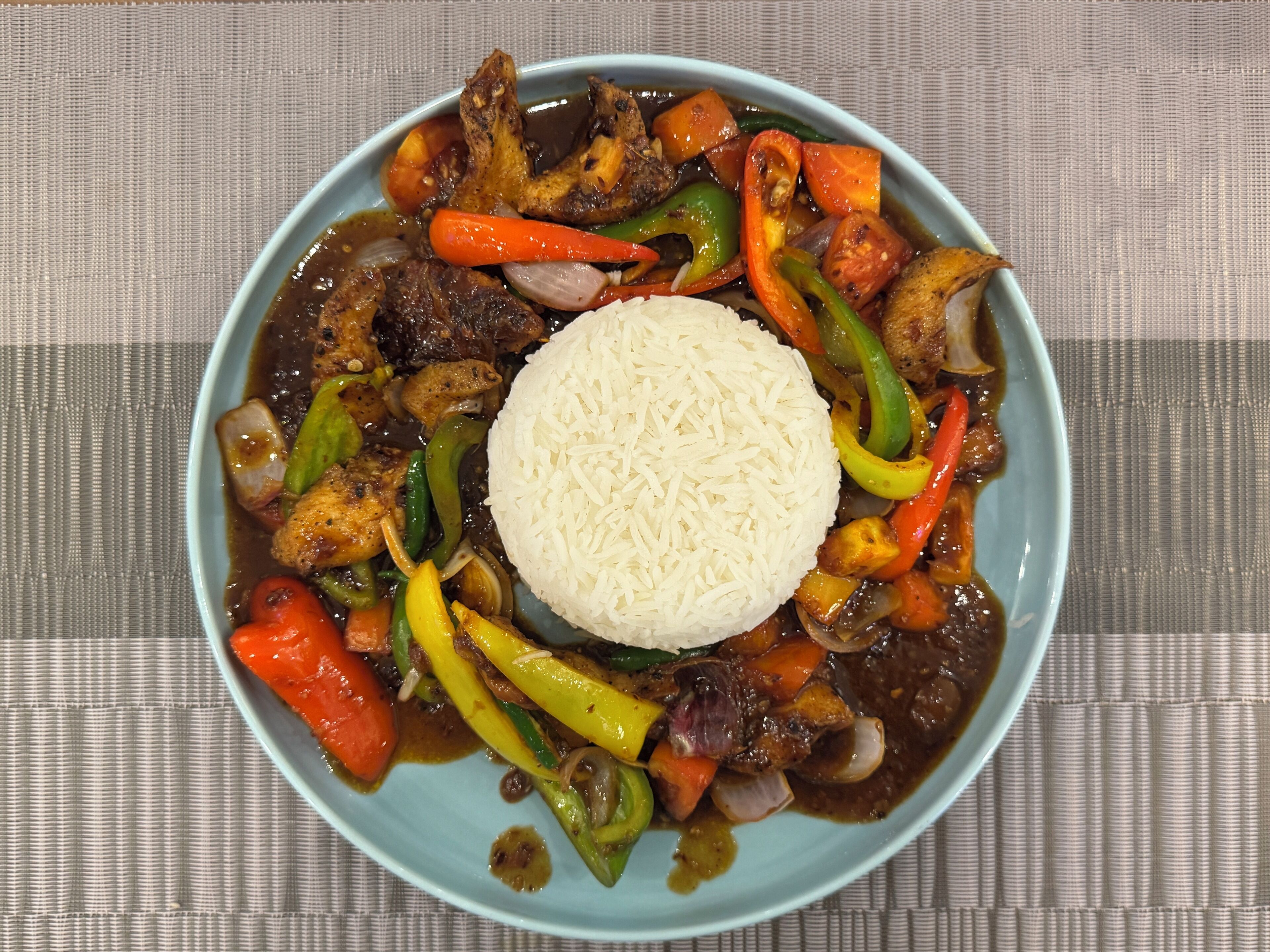 A bowl of food with rice and various vegetables and meat.