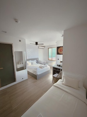 A modern hotel room with a large bed, a desk, a chair, and a window.