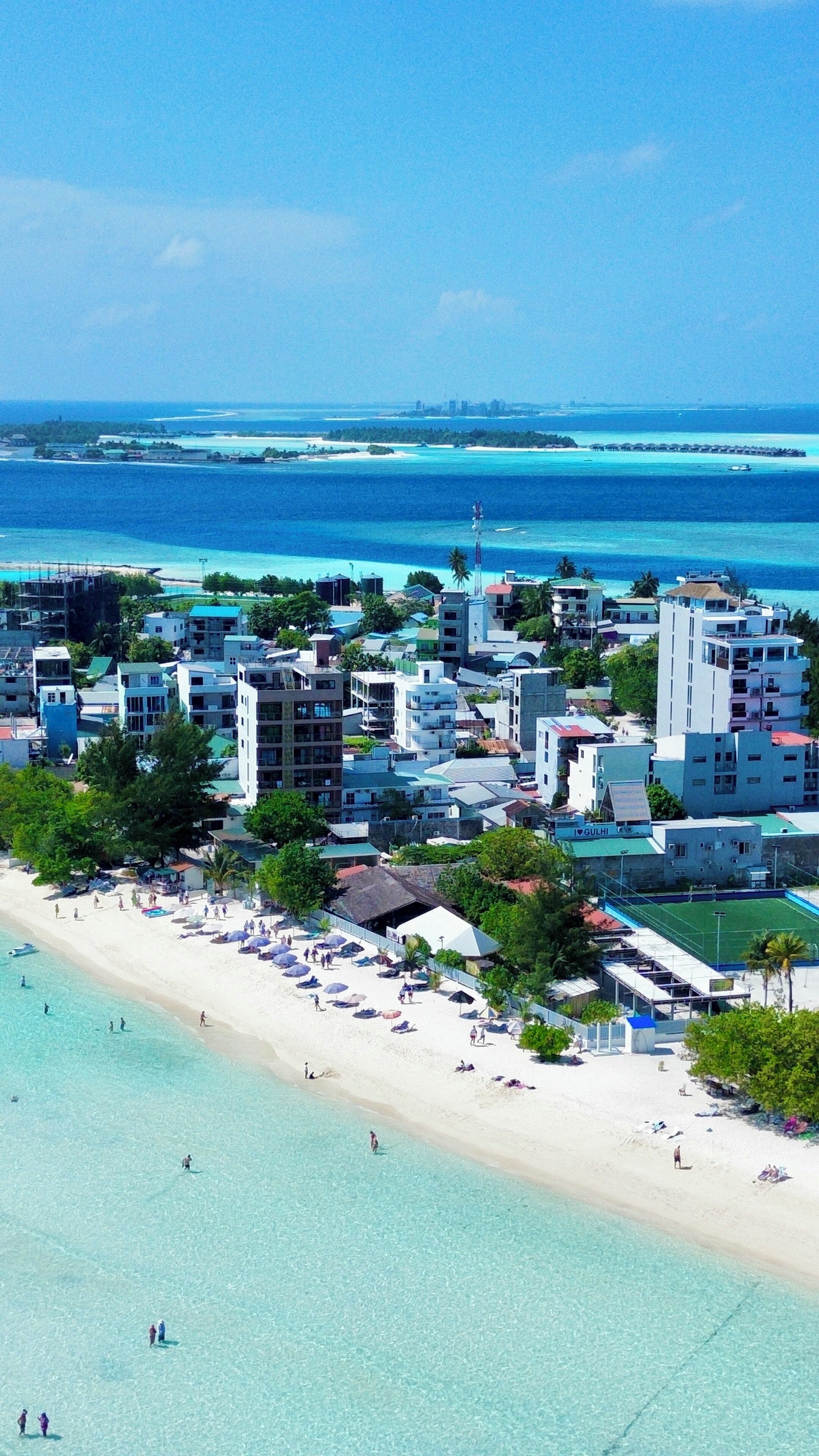 Un pueblo costero con playa, edificios y aguas azul turquesa.