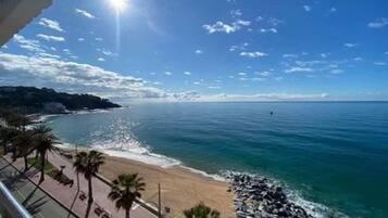 Una playa con cielo despejado, mar tranquilo y costa rocosa.