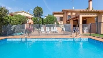 Una piscina con sillas de descanso y un patio cubierto.