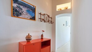 A hallway with a red cabinet, a framed photograph, and a wall-mounted decoration.