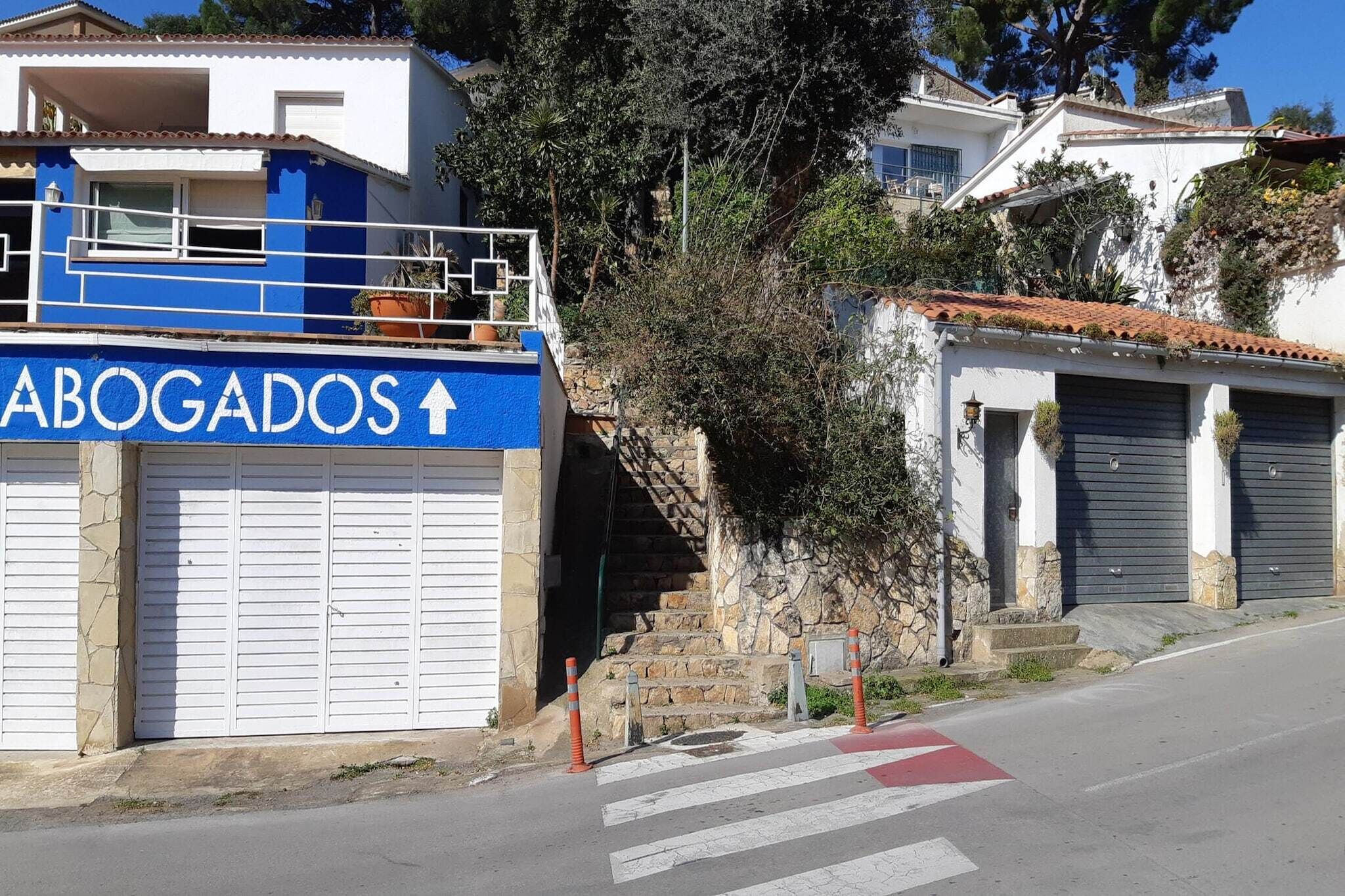 A building with a blue sign reading "ABOGADOS" and a staircase leading to a garage.
