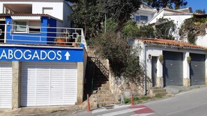 Un edificio con un letrero azul que dice "ABOGADOS" y una escalera que lleva a un garaje.