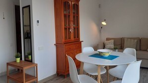 Un comedor con una mesa redonda blanca, sillas blancas, un aparador de madera y un sofá.