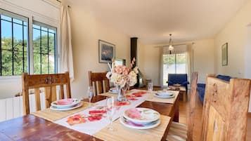 Een eethoek met een houten tafel voor vier personen, stoelen en een vaas met bloemen.