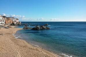 A beach with clear blue water, rocky outcrops, and buildings along the shore. - Villa in Llafranc near Sandy Beach (Llafranc)