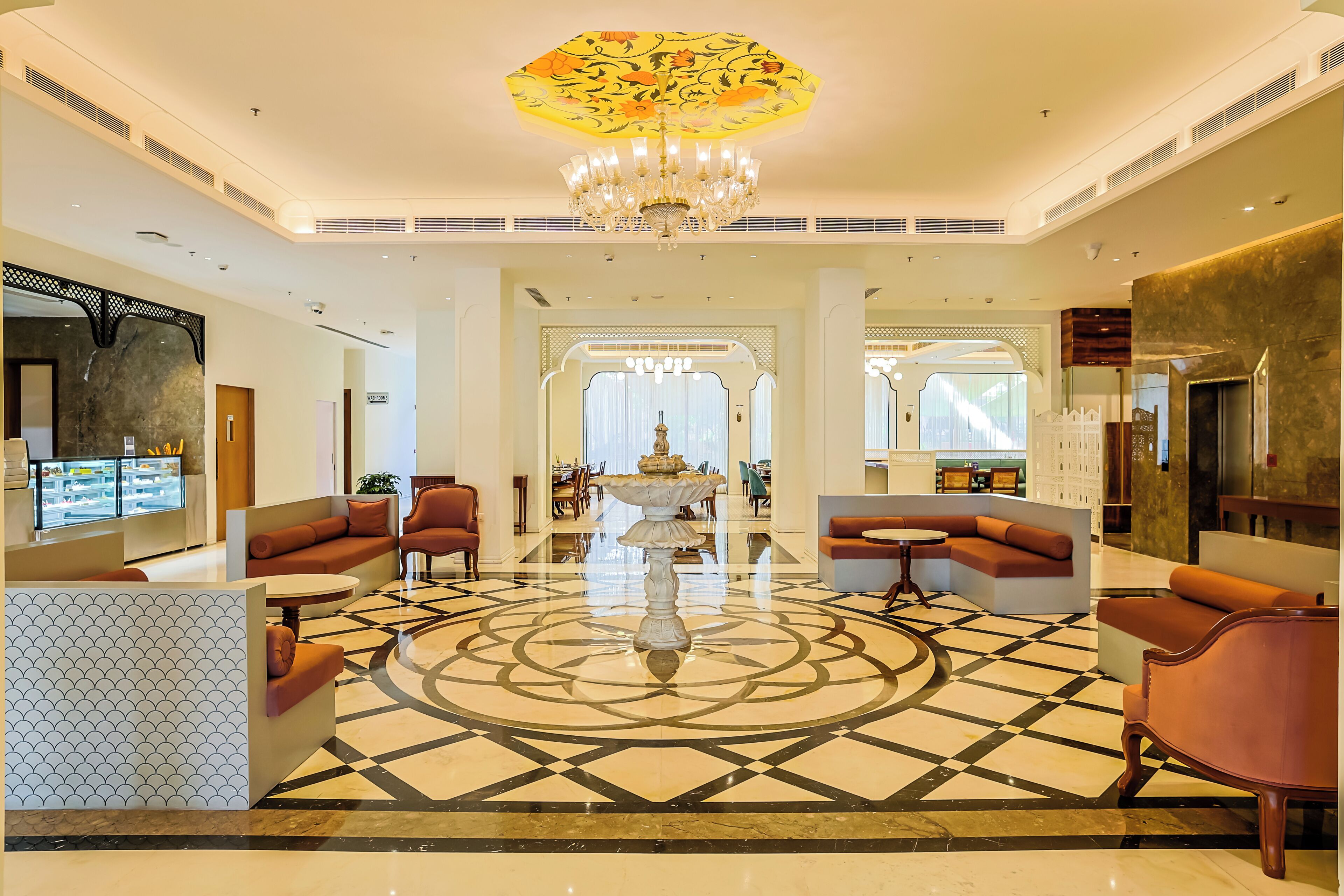 A spacious lobby with a central fountain, seating areas, and a patterned floor.