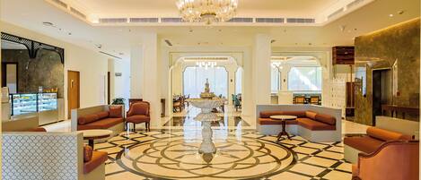 A spacious lobby with a central fountain, seating areas, and a patterned floor.