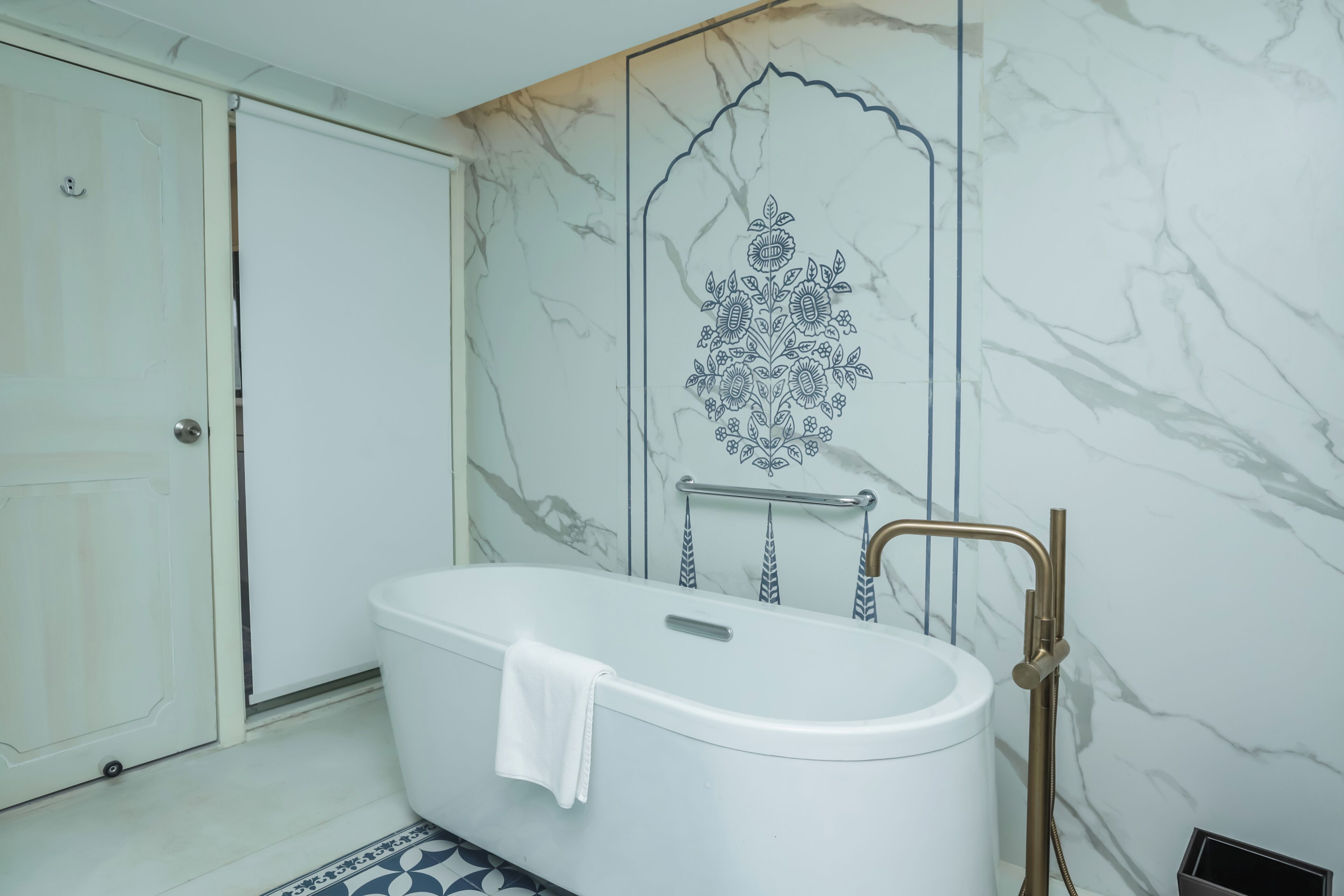 Une salle de bain avec une baignoire sur pieds, une serviette posée sur le bord, et une douche dotée d’un robinet doré.