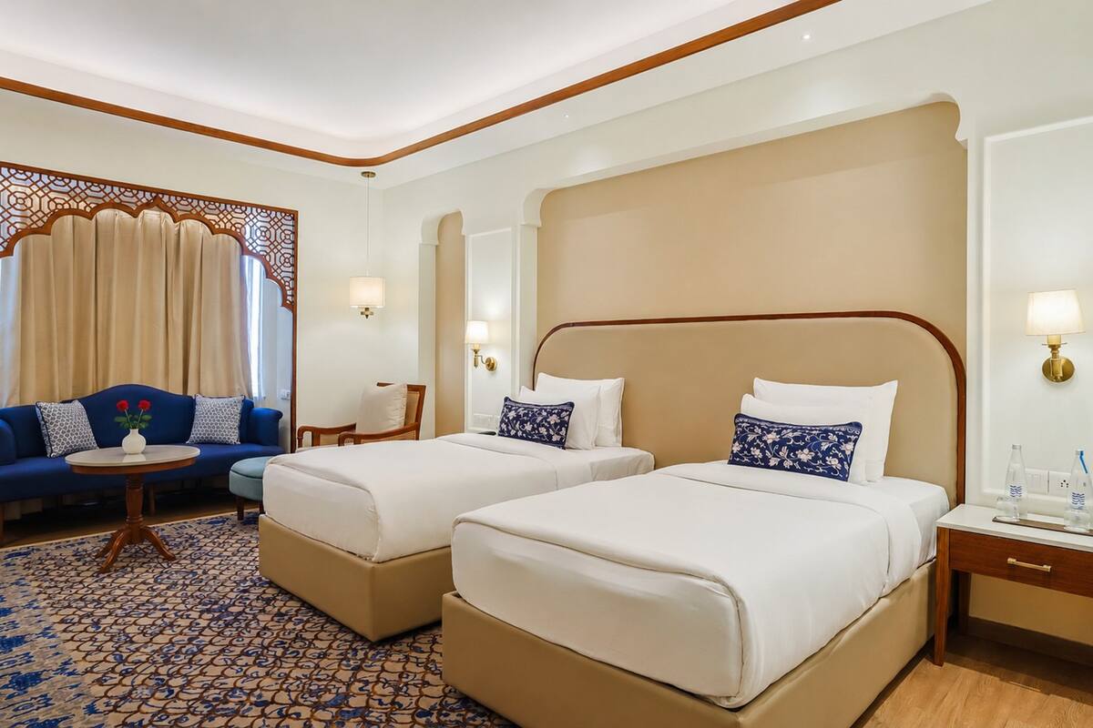 A hotel room with two beds, a sofa, a small table, and a decorative partition.
