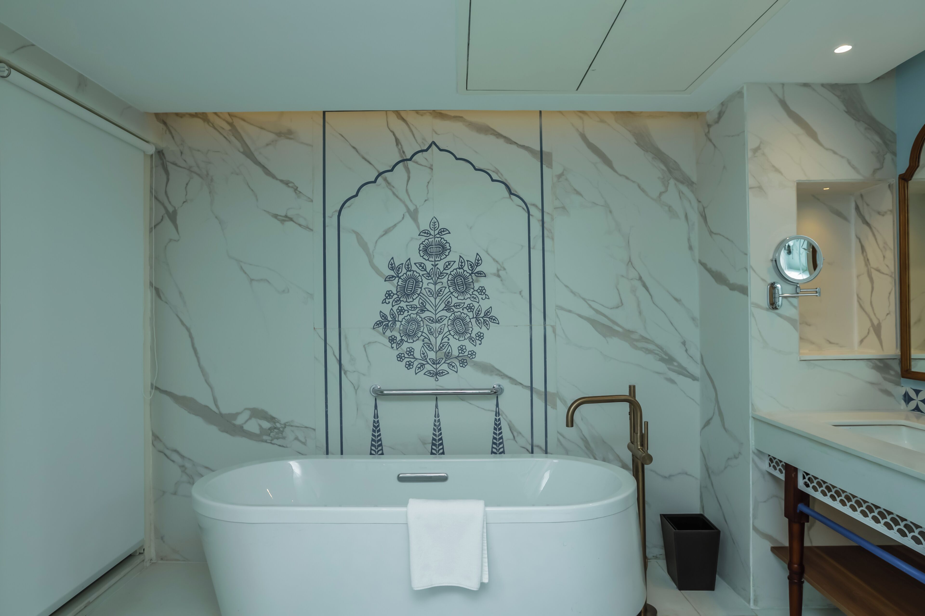 Un baño moderno con una bañera independiente, un tocador con espejo y un panel decorativo en la pared.