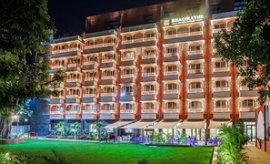 A multi-story hotel with balconies, a well-maintained lawn, and outdoor seating areas. - Bhagirathi By Atishay (Haridwar)