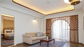 Una sala de estar moderna con un sofá, una mesa de centro, un tapete estampado y un biombo decorativo.
