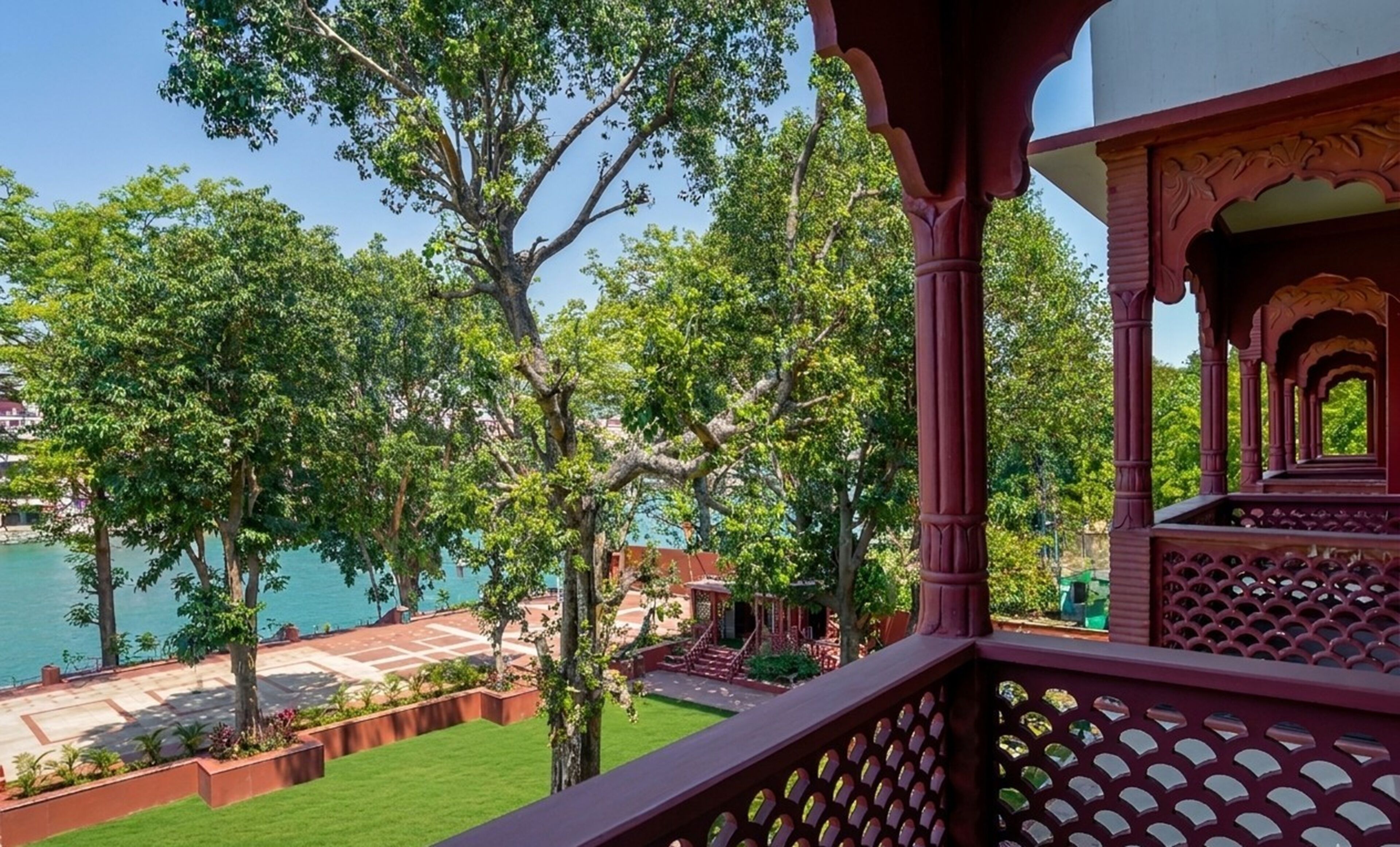 A balcony with a view of a body of water, trees, and a building with traditional architecture.