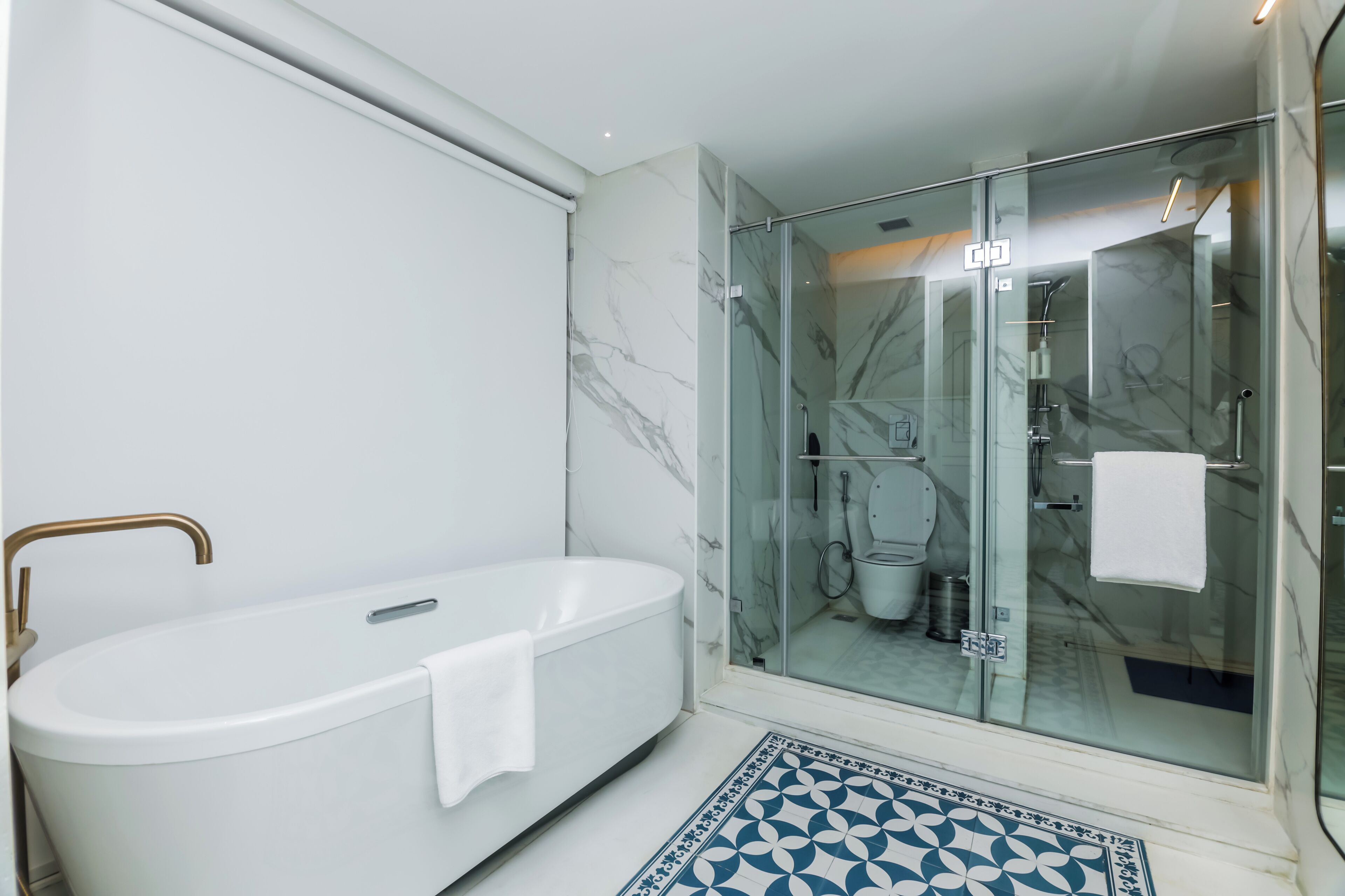 A modern bathroom with a freestanding bathtub, a glass-enclosed shower, and a patterned floor.