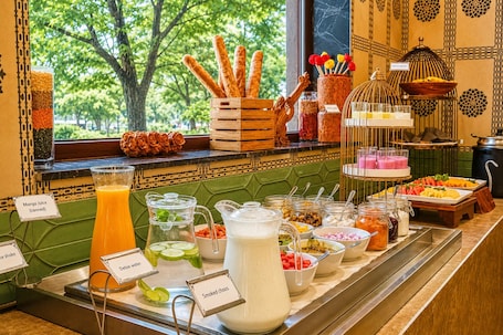 A buffet with various food and drink options, including smoked chicharrones, mango juice, and a pitcher of milk.. Bhagirathi By Atishay