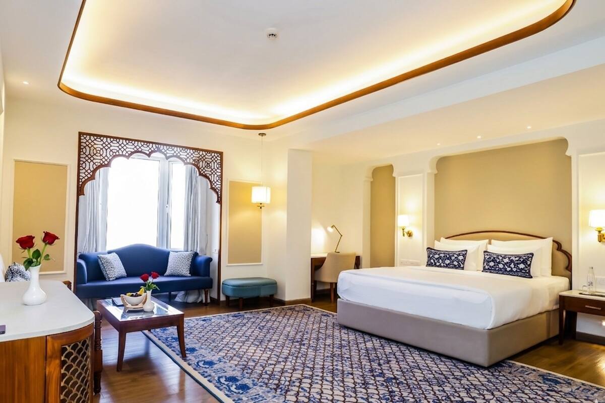 A hotel room with a bed, a sofa, a desk, and a decorative screen.