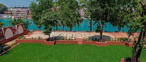 A well-maintained lawn, trees, and a view of a body of water.
