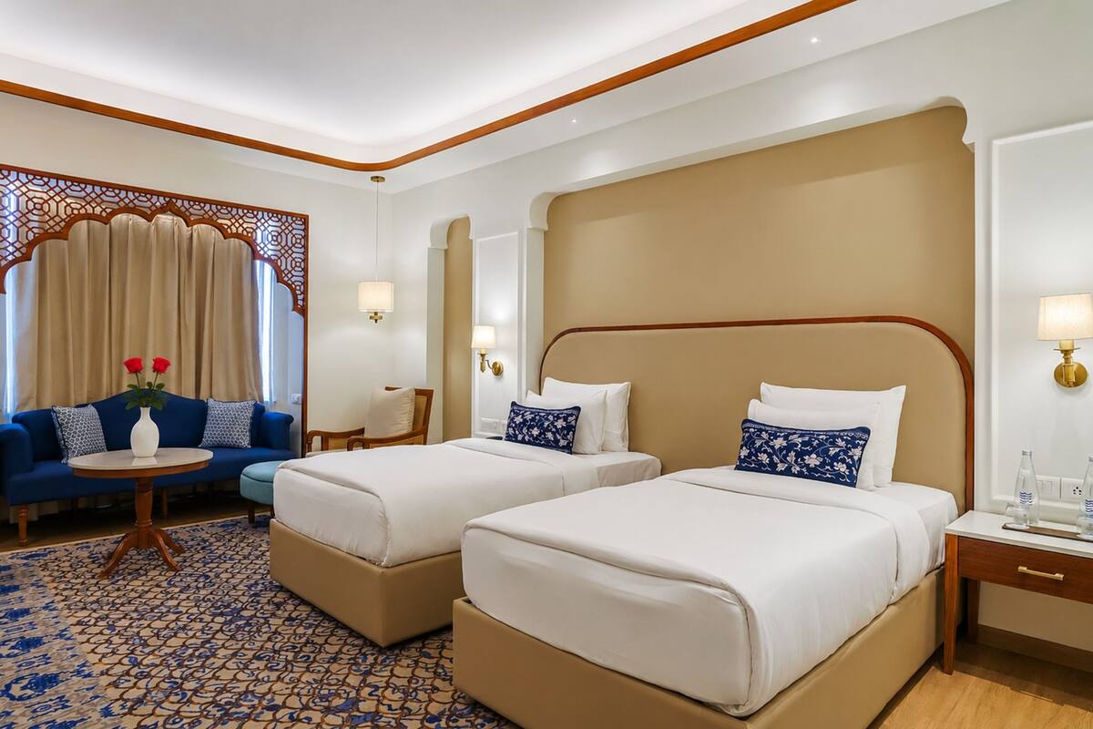 A hotel room with two beds, a sofa, a small table, and a decorative screen.