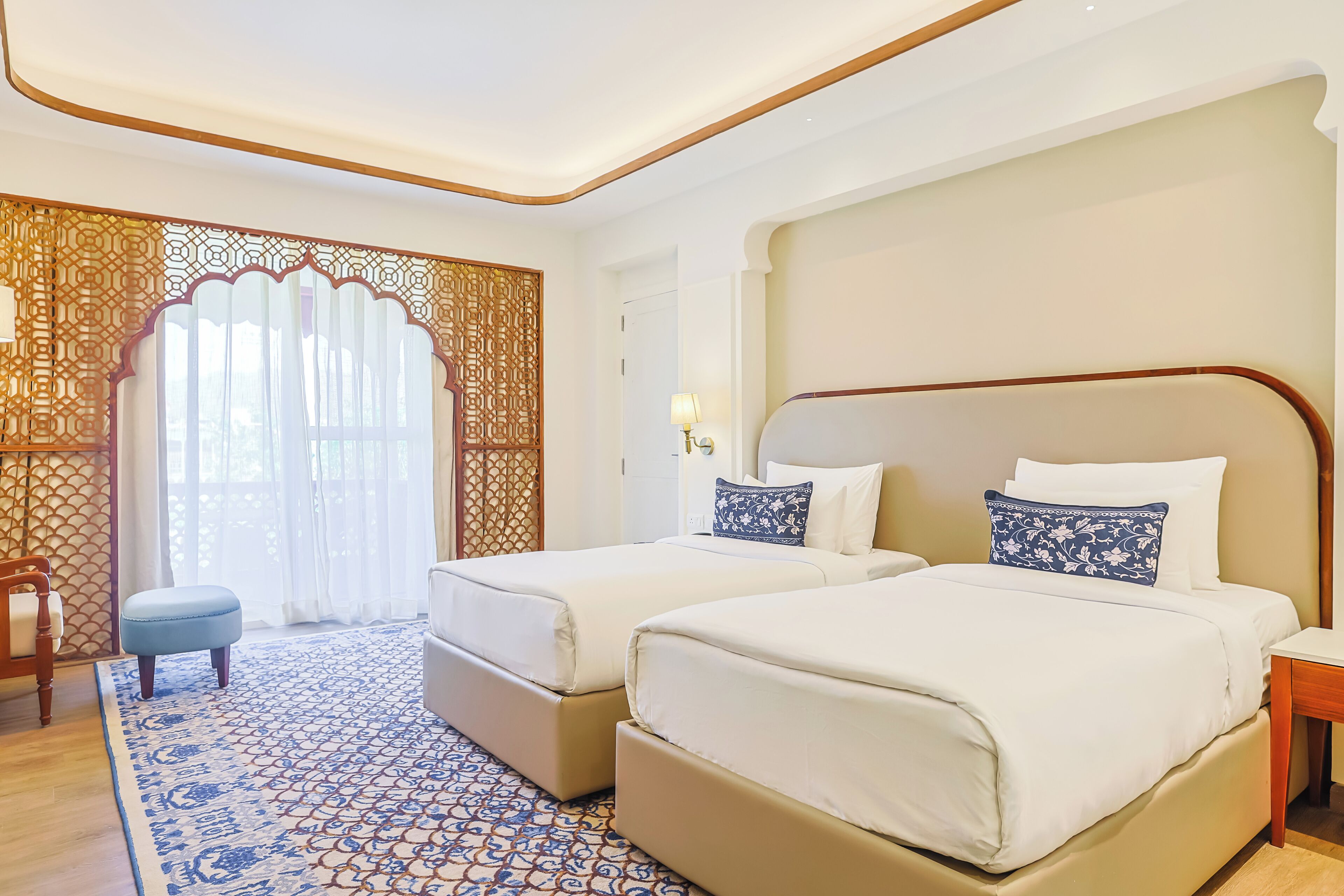 Une chambre d’hôtel avec deux lits, un tapis à motifs et un paravent décoratif.