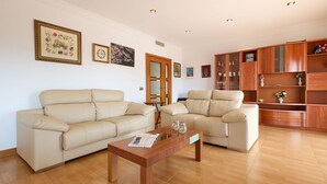 A living room with two beige sofas, a wooden coffee table, and a wooden cabinet with glass doors. - Apartment in Blanes with Sea View Terrace (Blanes)