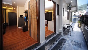 A modern interior with a wooden floor, a sliding glass door leading to a balcony with outdoor seating. - Friends Apartment Pvt.Ltd  (Nagarjun)