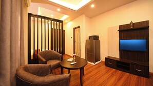 A modern living room with a flat-screen TV, a wooden entertainment unit, two armchairs, a small table, and a sliding door. - Friends Apartment Pvt.Ltd  (Nagarjun)
