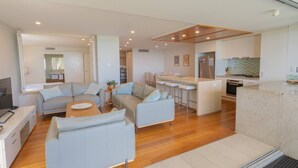 A modern living room with a sofa set, a dining area, and a kitchen with a bar.