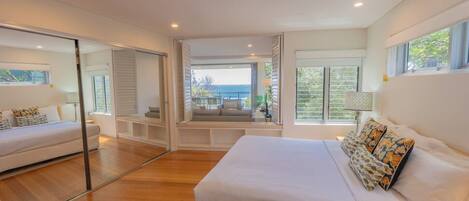Une chambre moderne avec un grand lit, un canapé et un balcon offrant une vue sur la mer.