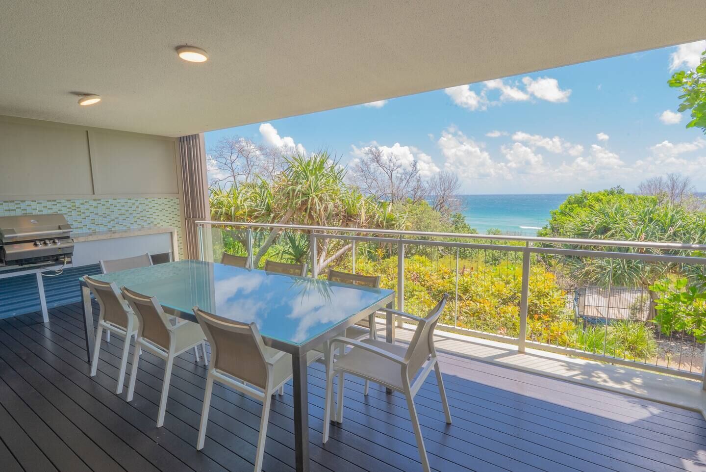 Ein Balkon mit Glastisch und Stühlen, der einen schönen Meerblick bietet.