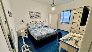 A bedroom with a bed, a desk, a chair, a wardrobe, and a window with a view. - Villa Ravello - beach (ravello)