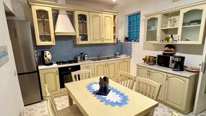 A compact kitchen with a dining table, chairs, and a chandelier. - Villa Ravello - beach (ravello)