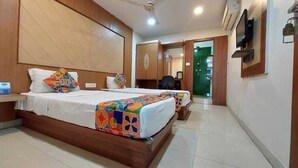 Une chambre d’hôtel avec deux lits, une tête de lit en bois, un bureau avec une chaise et un miroir au mur.