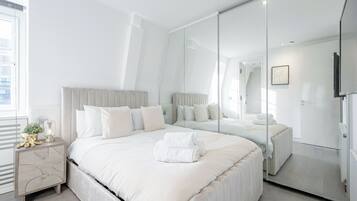 Une chambre moderne avec un grand lit, une table de chevet, un miroir et une vue sur la ville.