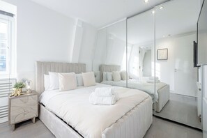 Une chambre moderne avec un grand lit, une table de chevet, un miroir et une vue sur la ville.
