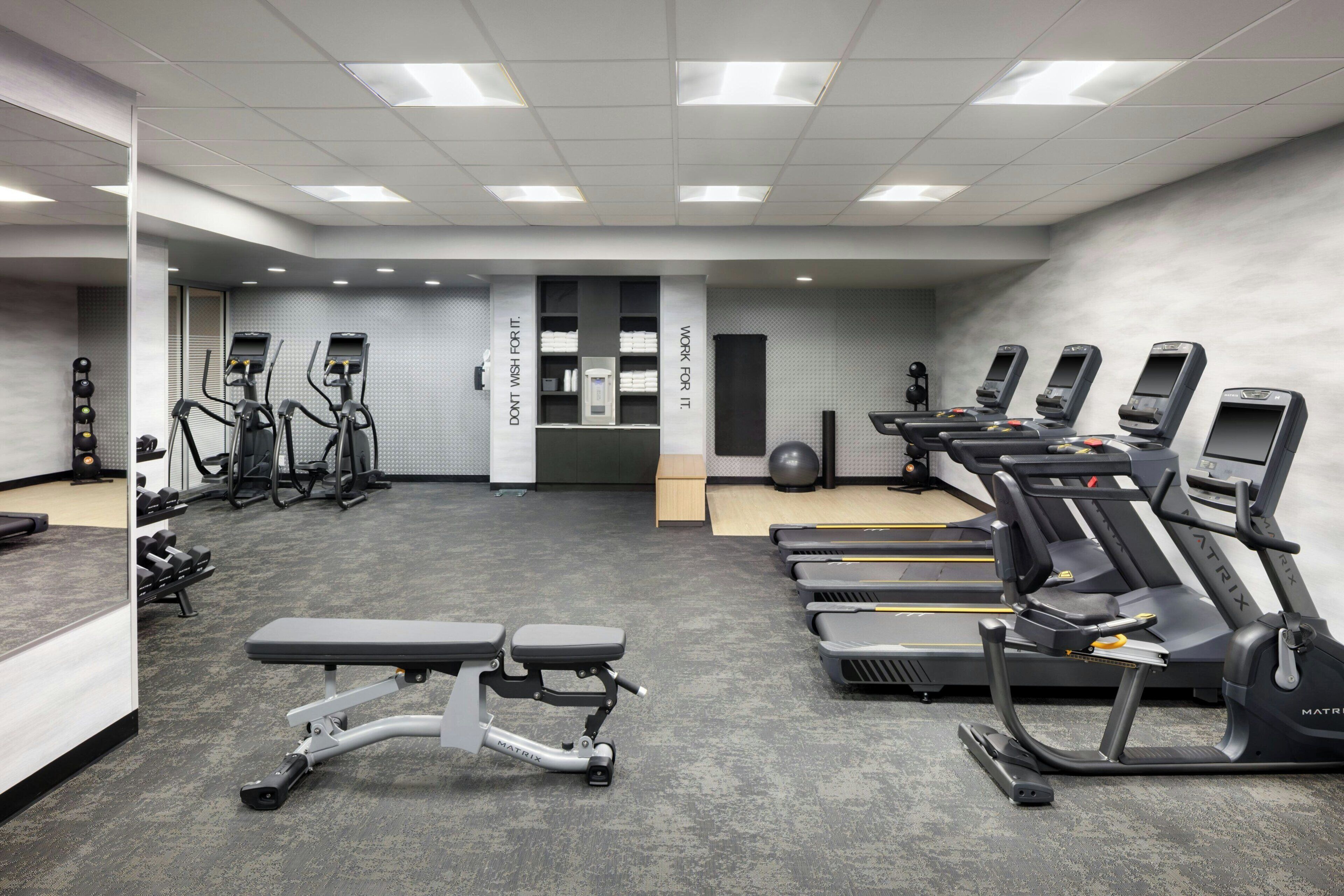 A gym with treadmills, elliptical machines, and free weights.