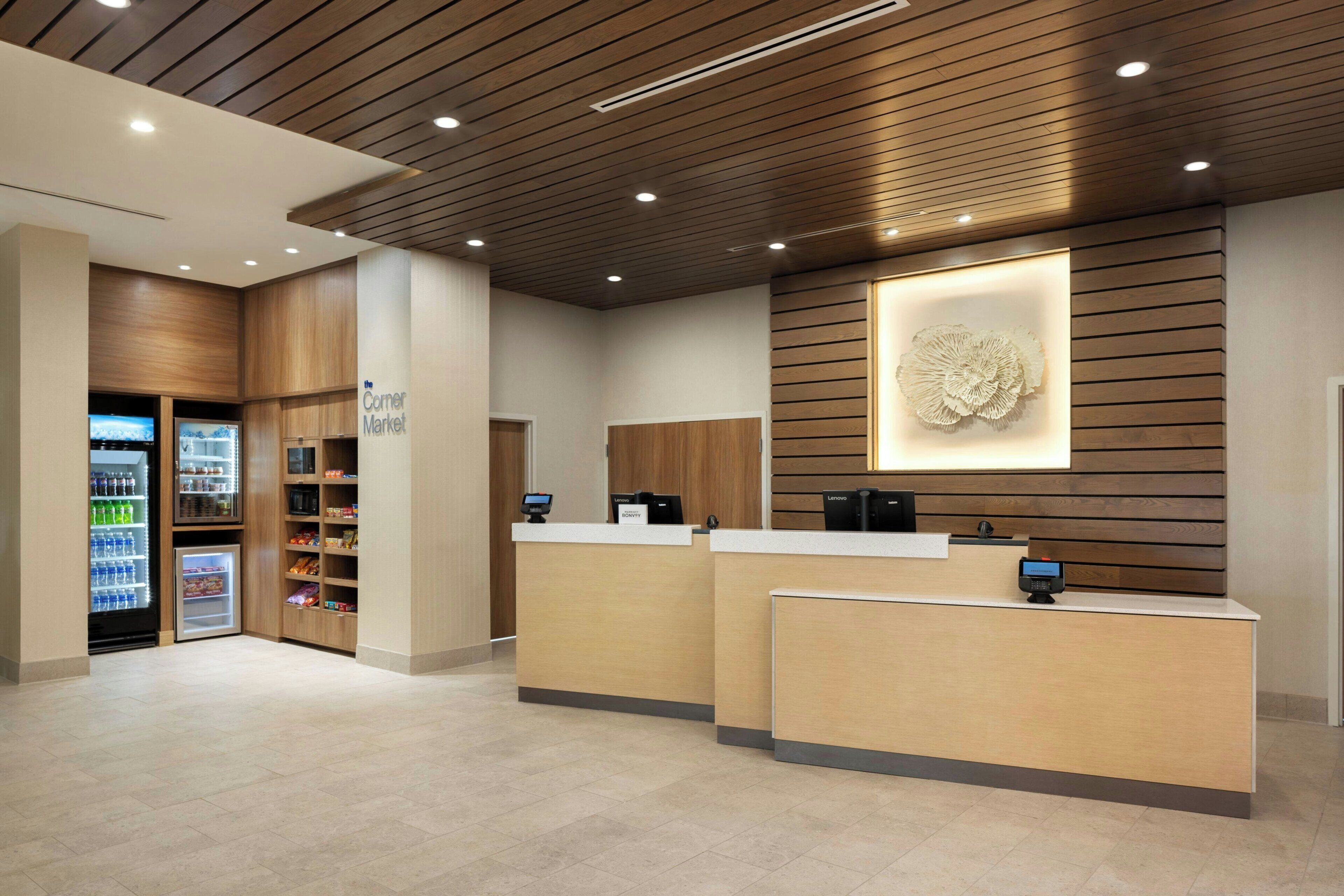 A reception area with a counter, a refrigerator stocked with beverages, and a wall-mounted decorative piece.