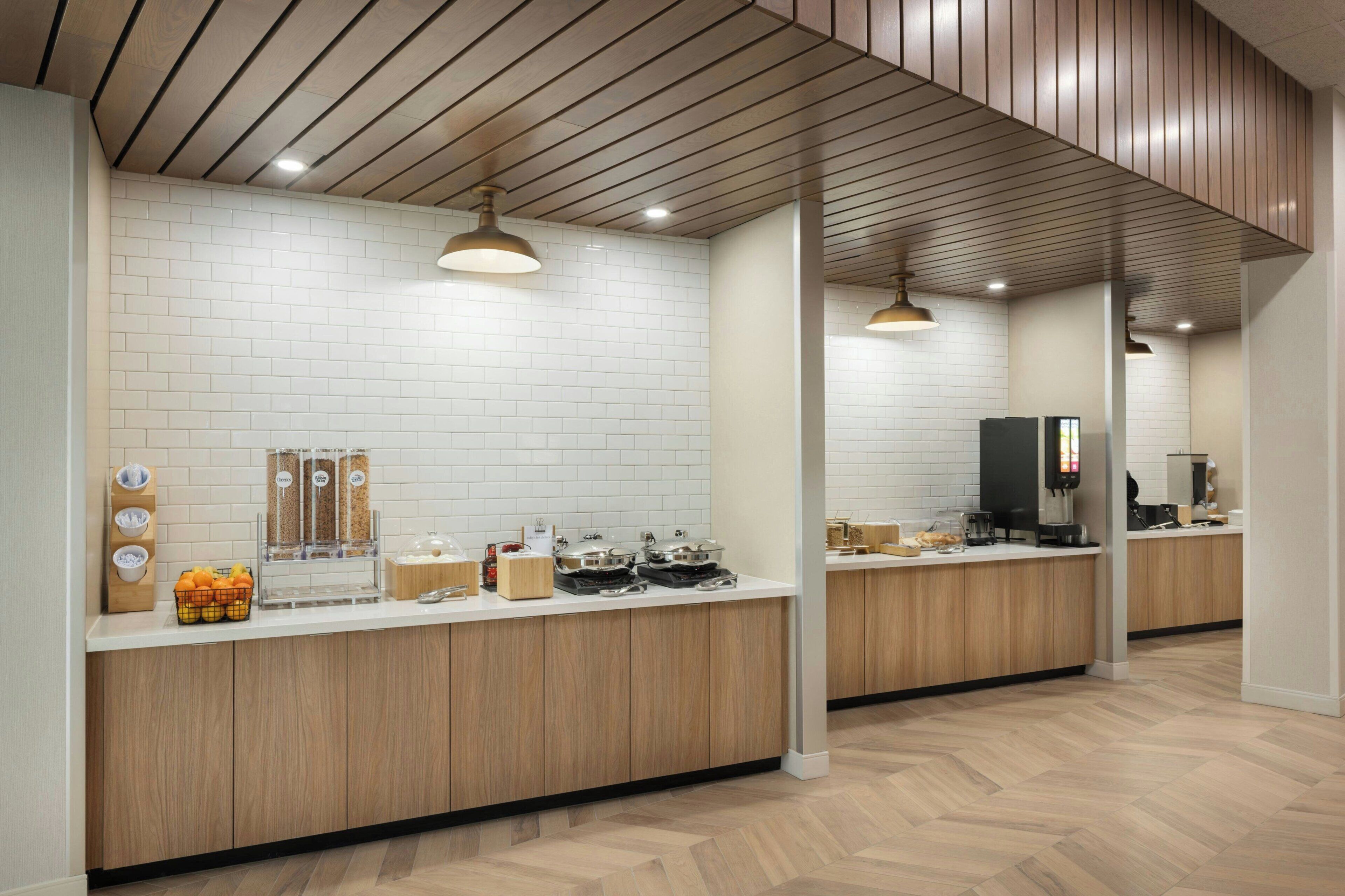 Una cocina moderna con paredes de azulejos blancos, encimeras de madera y un suelo con motivo de espiga.