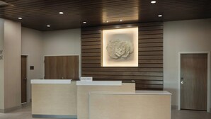 A reception desk with a wooden panel wall and a recessed light above it. -  Fairfield Inn & Suites by Marriott Melbourne Beach (Indialantic)