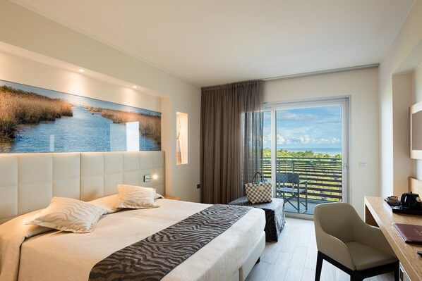 Ein Hotelzimmer mit einem großen Bett, einem Schreibtisch und einem Balkon mit Blick.