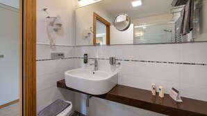 Un baño moderno con un lavamanos blanco, un espejo y un perchero para toallas.